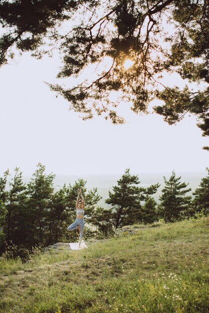 Une jeune femme pratique le yoga et médite dans les montagnes au coucher du soleil Paix et unité avec la nature