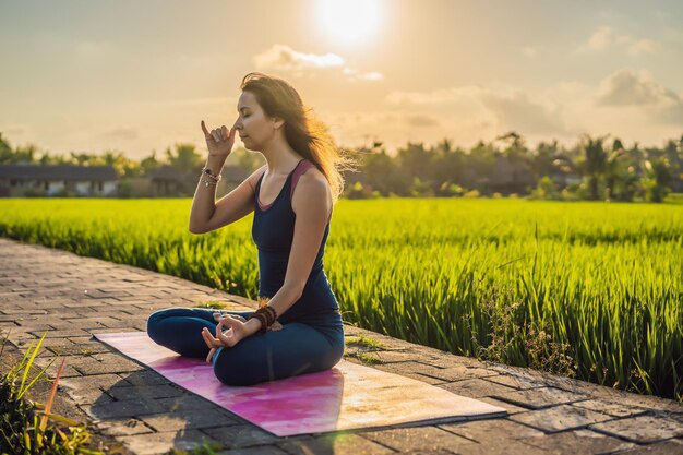 Jeune femme pratique le yoga en plein air dans les rizières le matin pendant une retraite de bien-être à Bali