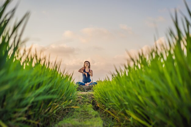 Jeune femme pratique le yoga en plein air dans les rizières le matin pendant une retraite de bien-être à Bali