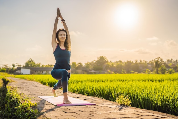 Photo jeune femme pratique le yoga en plein air dans les rizières le matin pendant une retraite de bien-être à bali