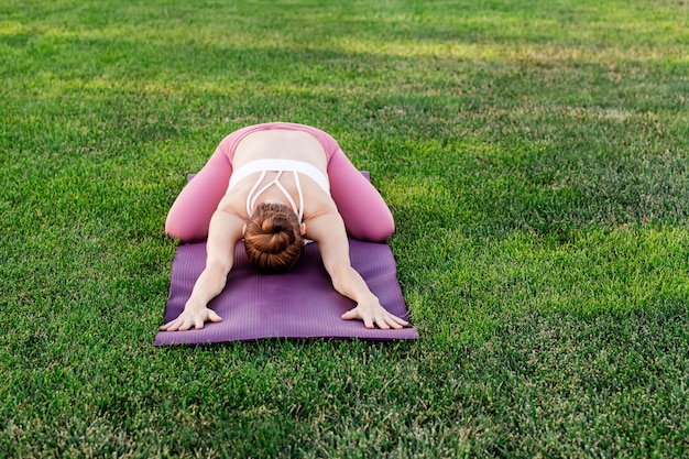 Jeune femme, pratiquer, yoga, sur, a, herbe verte, étirage, et, délassant, extérieur