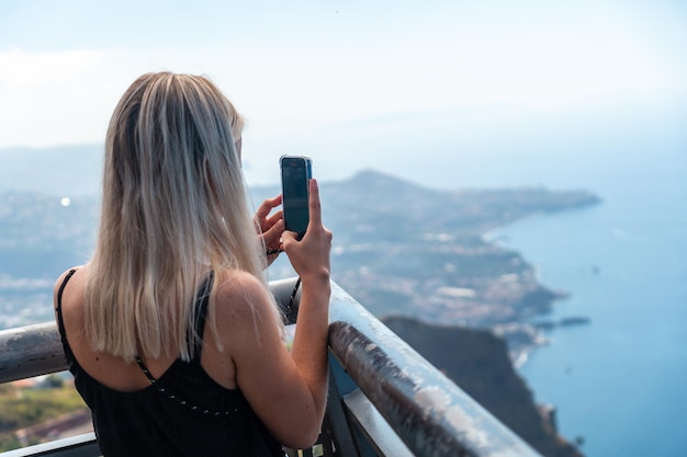 Une jeune femme prenant une photo du plus haut point de vue appelé Cabo Girao à Funchal Madère