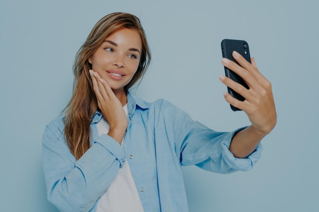 Jeune femme prenant une photo isolée sur fond bleu clair