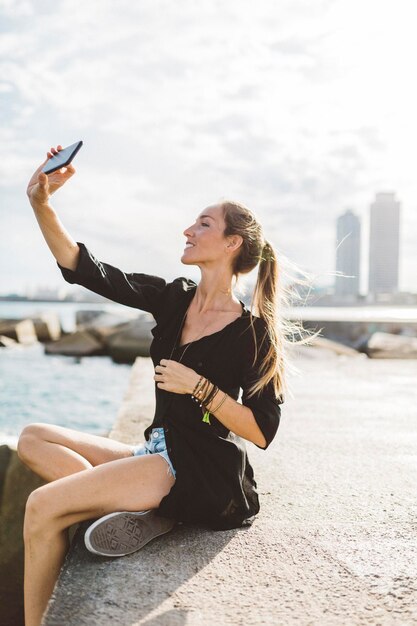 Jeune femme prenant un selfie au bord de la mer