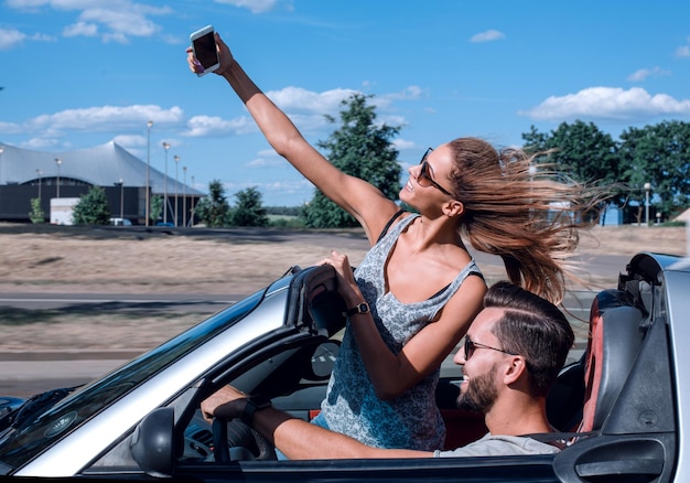 Jeune femme prenant un selfie dans la voiture