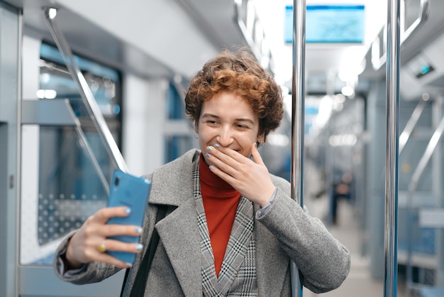 Jeune femme prenant un selfie debout dans une voiture de métro vide