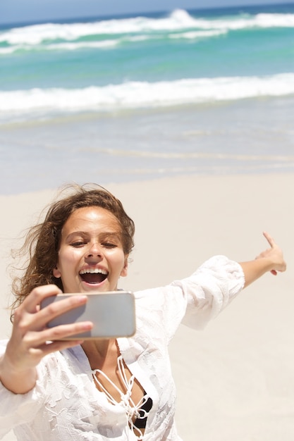 Jeune femme prenant selfie et pointant vers la mer