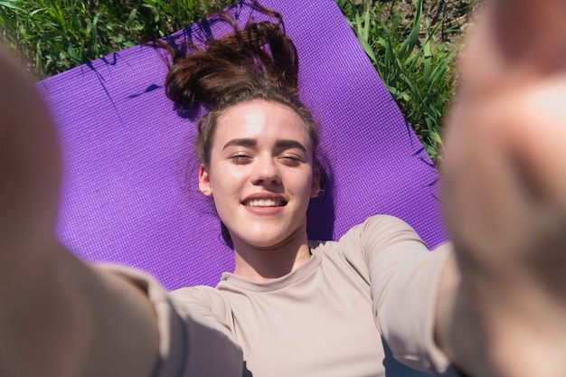 Jeune femme prenant un selfie sur un tapis de yoga