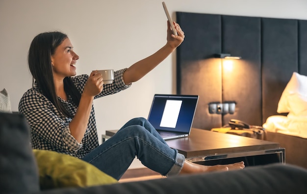 Une jeune femme prenant un selfie avec une tasse de café à la maison le matin