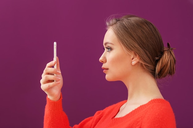 Jeune femme prenant selfie avec téléphone portable sur une surface de couleur