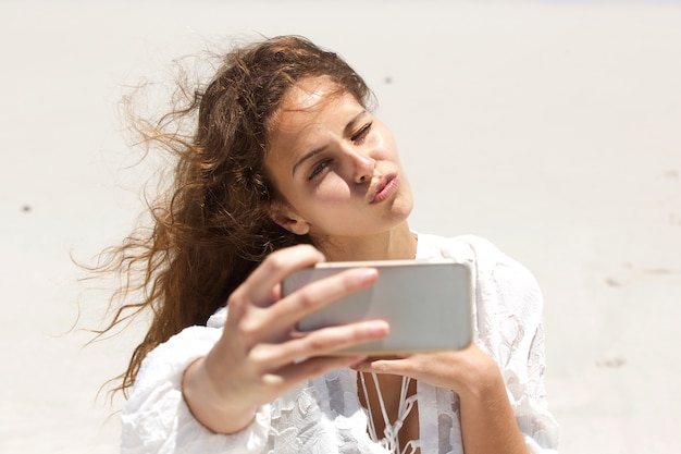 Jeune femme prenant selfie avec visage de baiser