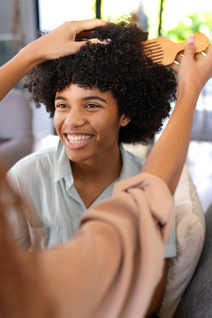 Photo jeune femme prenant soin des cheveux afro du garçon