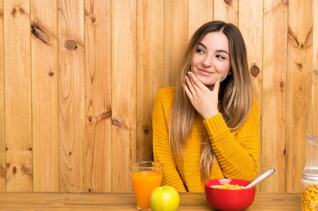 Jeune femme prenant son petit déjeuner dans une cuisine en pensant à une idée