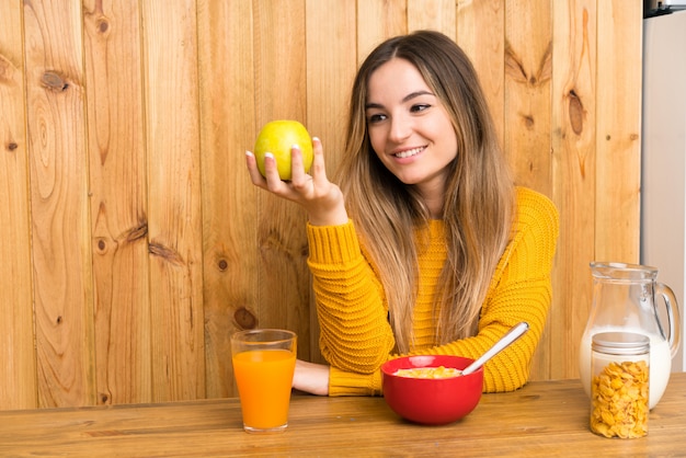 Jeune femme prenant son petit déjeuner dans une cuisine avec une pomme