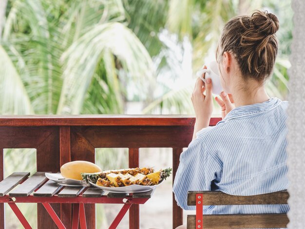 Une jeune femme prend le petit déjeuner dans un restaurant d'hôtel en plein air