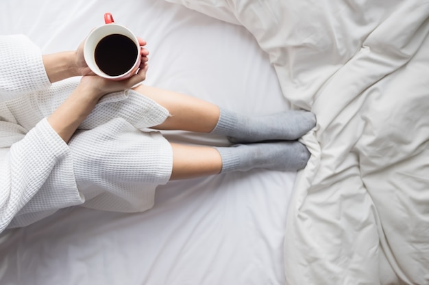 Une Jeune Femme Prend Son Café En Train De S'asseoir Sur Son Lit. Lazy Matin Ensoleillé Au Lit