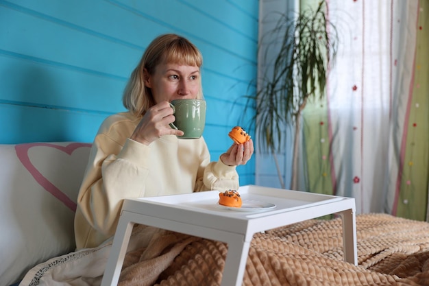 Jeune femme prend son petit déjeuner au lit