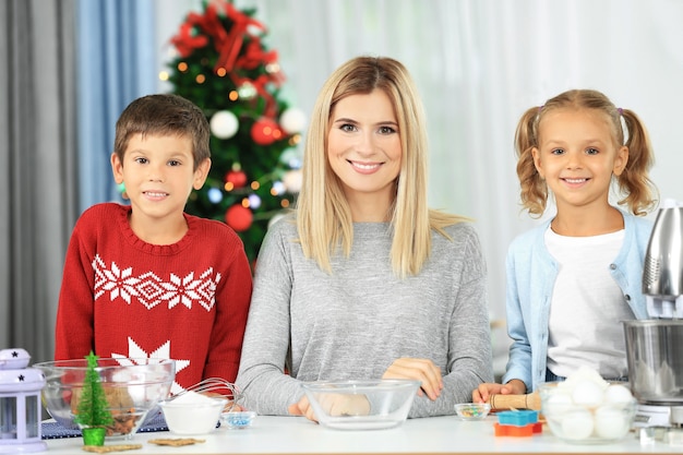 Jeune femme préparant des biscuits de Noël avec de petits enfants dans la cuisine