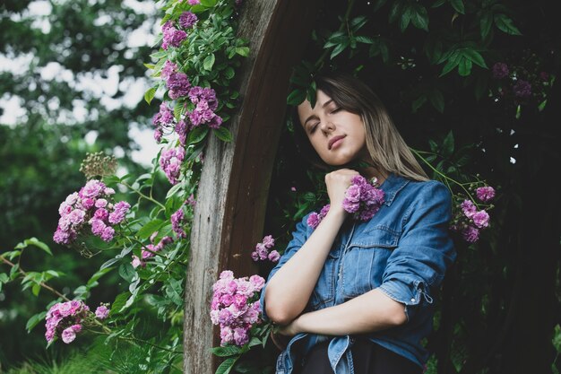 Jeune femme près de buisson de fleurs violettes dans un jardin