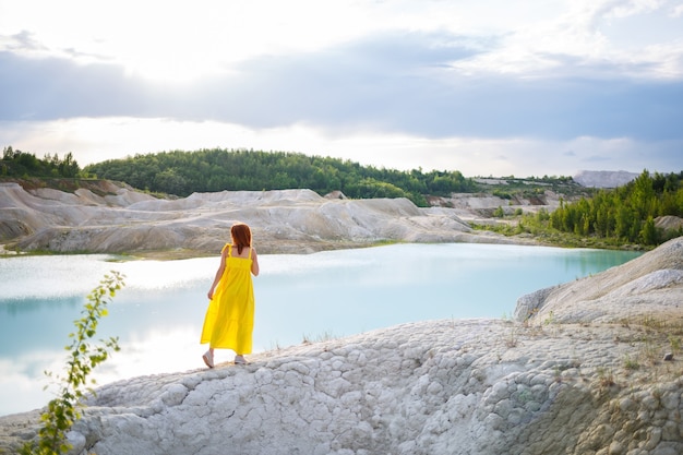 Jeune femme près d'un lac avec de l'eau azur et des montagnes pierreuses avec des arbres verts. Belle vue sur le lac dans la forêt