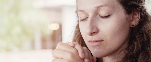 Jeune femme priant les yeux fermés