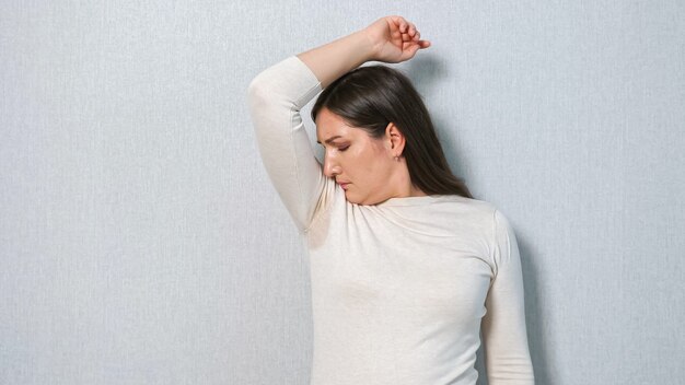 Jeune femme avec un problème de transpiration sous les aisselles. Le concept sent mauvais. Hyperhidrose.