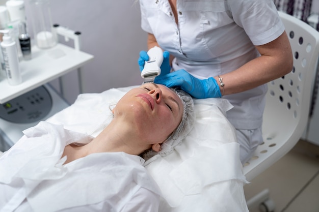 Jeune femme sur la procédure de nettoyage de la peau du visage chez l'esthéticienne