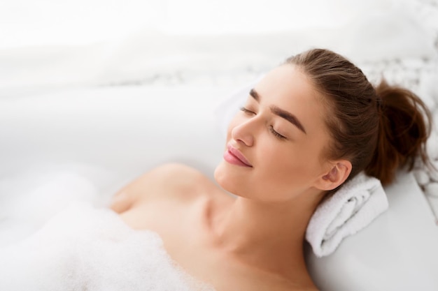 Jeune femme profitant d'un bain agréable avec de la mousse