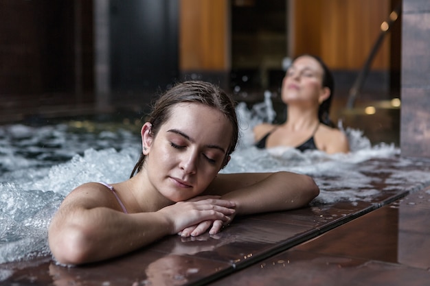 Jeune femme profitant de l'eau bouillonnante dans le centre de spa