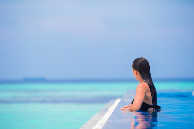 Jeune femme profitant de l'eau et se reposer dans la piscine extérieure