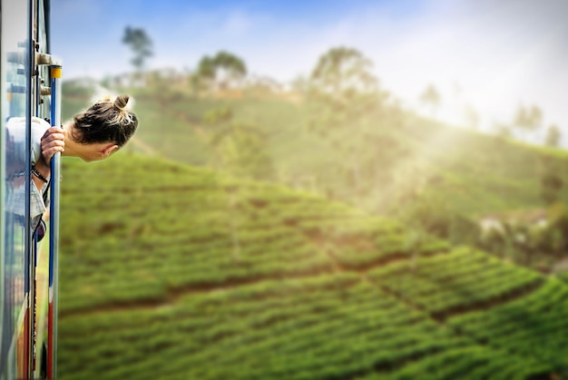 Photo une jeune femme profitant d'un trajet en train d'ella à kandy parmi les plantations de thé au sri lanka