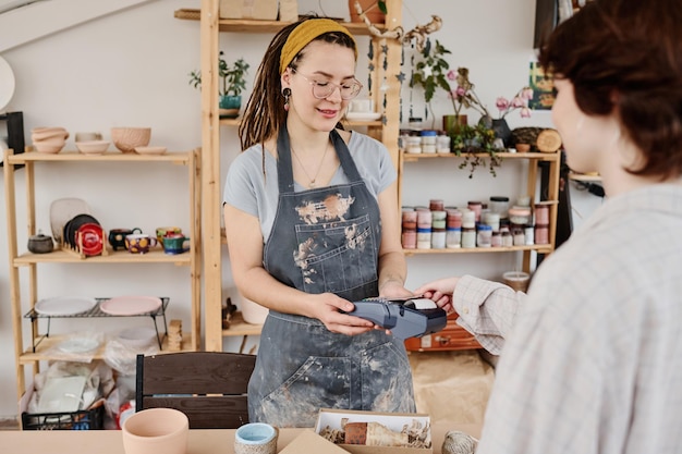 Jeune femme propriétaire d'un petit magasin de faïence vendant des articles faits à la main