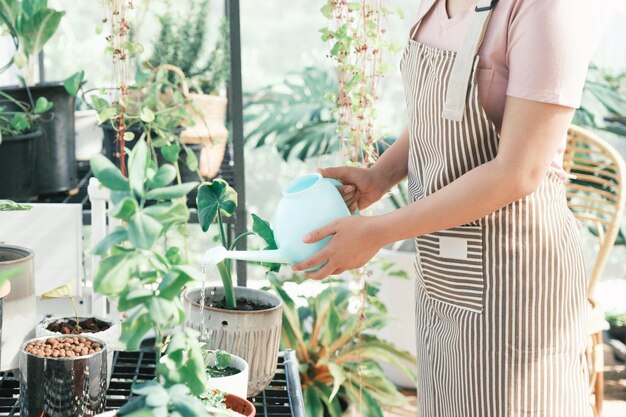 Jeune femme propriétaire d'usine shop arrosage des plantes dans un magasin de plantes