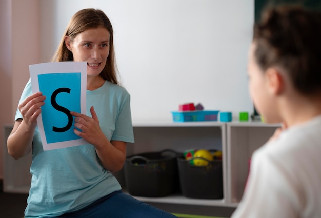 Jeune femme psychologue aidant une fille en orthophonie