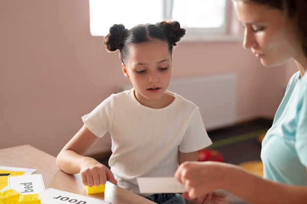 Jeune femme psychologue aidant une fille en orthophonie