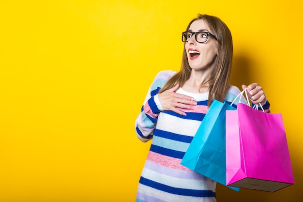 Jeune femme en pull détient des sacs à provisions