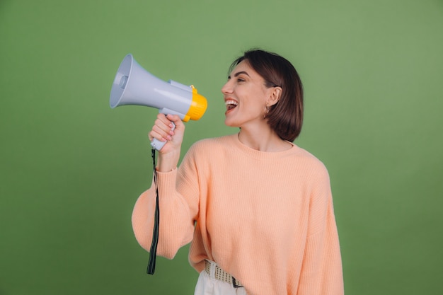 Jeune femme en pull pêche occasionnel isolé sur un mur de couleur olive verte