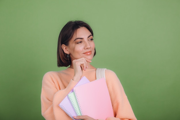 Jeune femme en pull pêche occasionnel isolé sur un mur de couleur olive verte