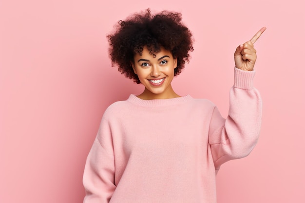 Une jeune femme en pull rose pointe vers le ciel.