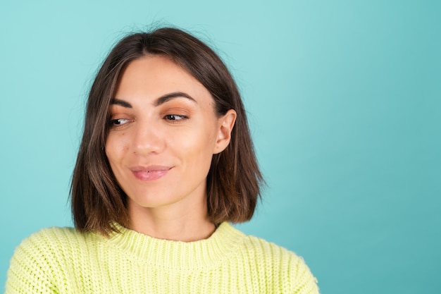 Jeune femme en pull vert clair souriant