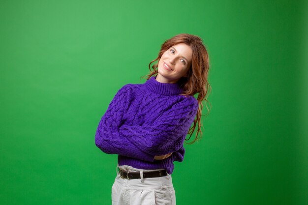 jeune femme en pull violet sur fond vert studio