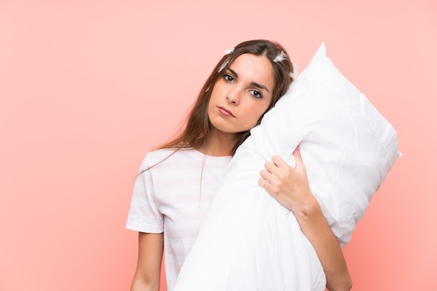 Jeune femme en pyjama sur mur rose isolé