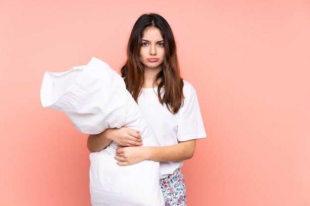 Jeune femme en pyjama sur mur rose triste