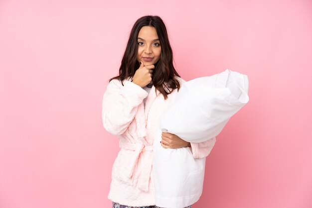 Jeune femme en pyjama sur la pensée de mur rose