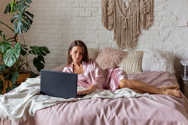 Jeune femme en pyjama rose allongé sur le lit à la maison