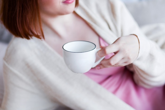 Jeune Femme En Pyjama Rose Et Cardigan Blanc Tenant Une Tasse à La Main. Photo