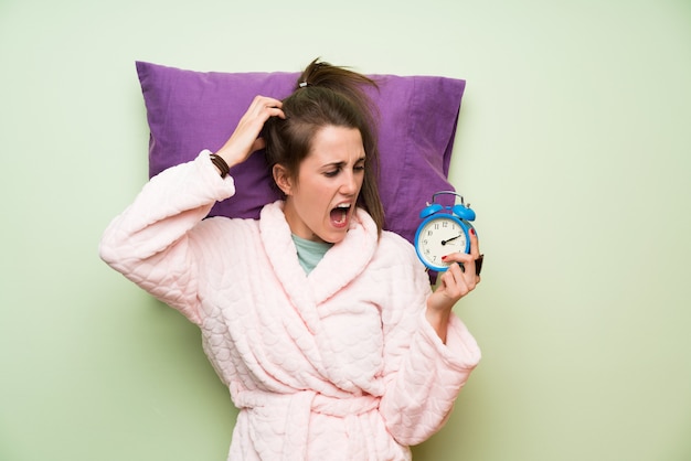 Jeune femme en pyjama tenant une horloge vintage