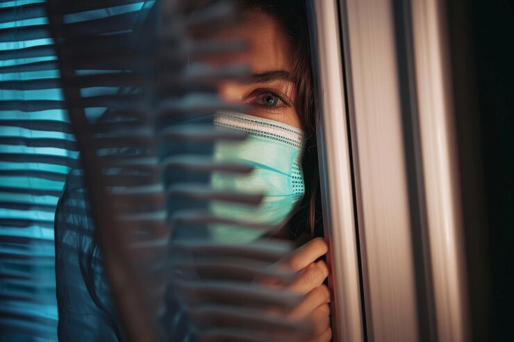Photo une jeune femme en quarantaine portant un masque et regardant par la fenêtre