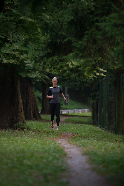 Jeune femme qui court dans une zone forestière boisée - Entraînement et exercice pour l'endurance du marathon de course à pied - Concept de mode de vie sain et de remise en forme
