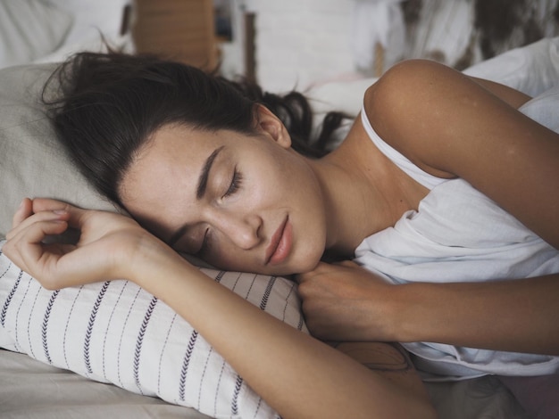 Photo une jeune femme qui dort sur le lit.